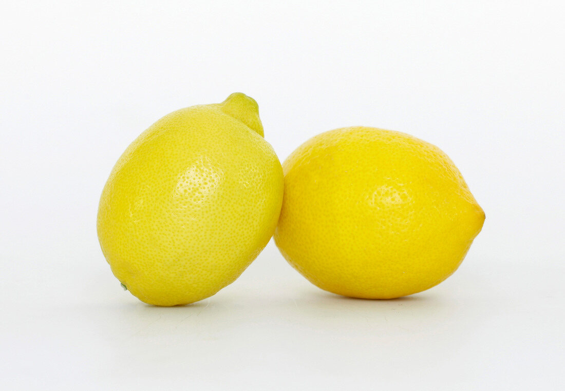 Close-up of two fresh whole lemons on white background