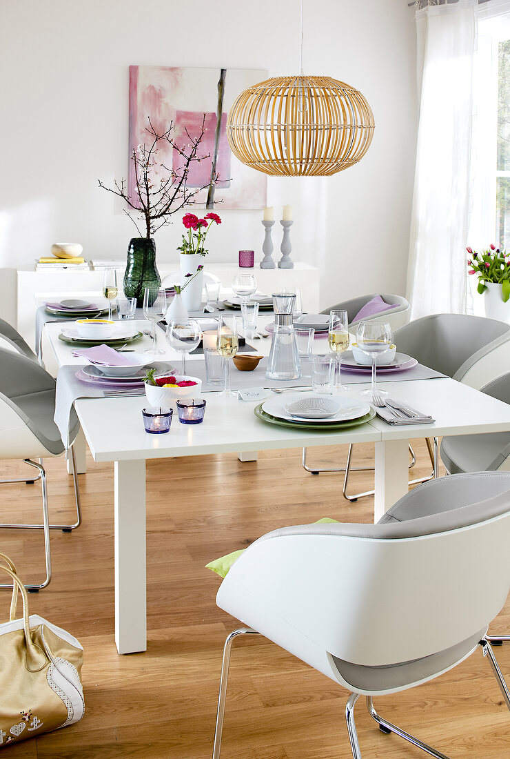 Dining table with table setting, lit candles and wooden lamp