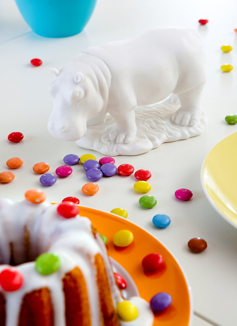 Porzellan-Nilpferd auf mit Süßigkeiten dekoriertem Tisch