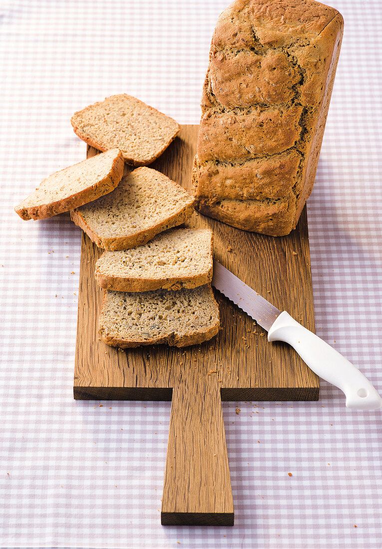 Loaf of bread and slices of bread on chopping board