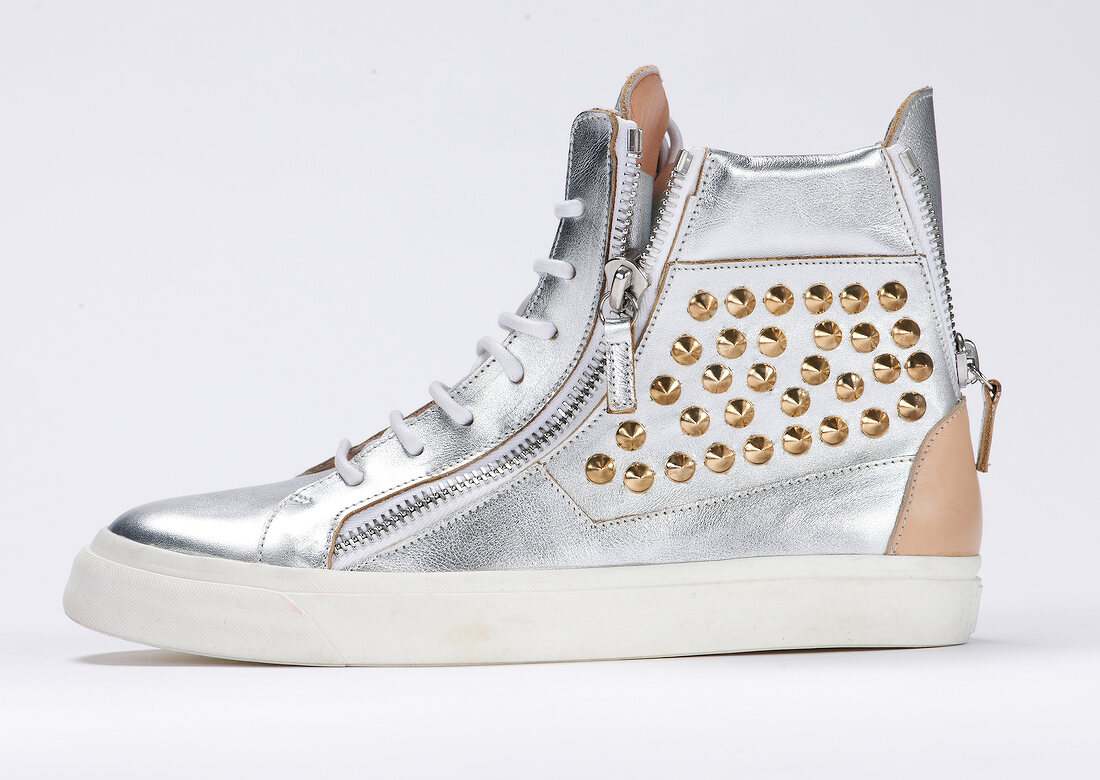 Silver sneaker with golden rivets on white background