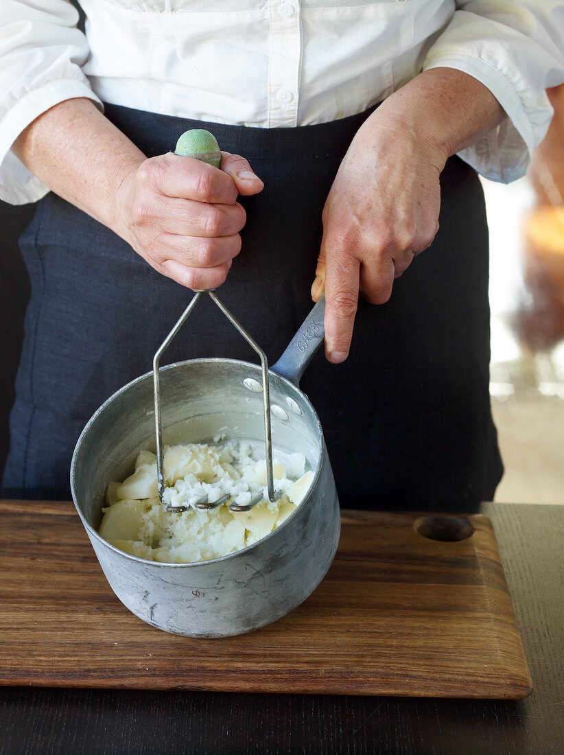 Close-up of hand mashing puree in sauce pan, step 3