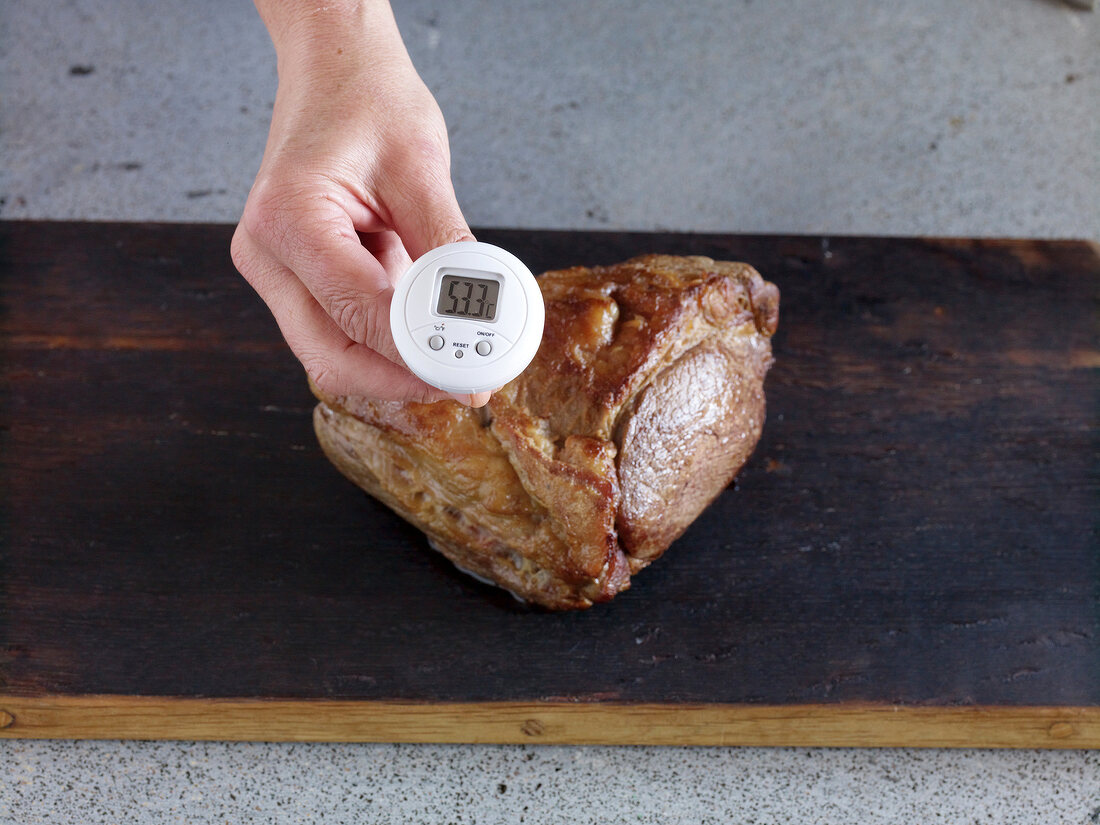 Close-up of hand measuring temperature of roasted beef, step 3