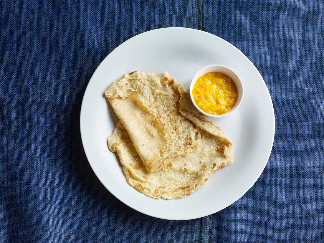 Sesame pancake on plate with mango ragout in bowl