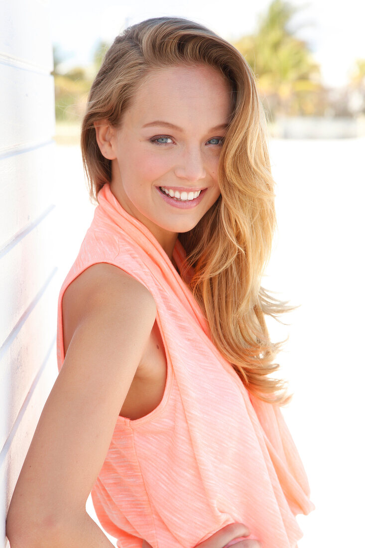 Portrait of beautiful blonde woman wearing apricot colour blouse, smiling