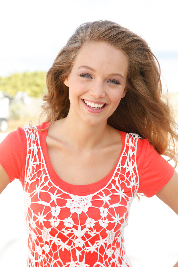 Portrait of pretty woman wearing orange-shirt and white fishnet top, smiling