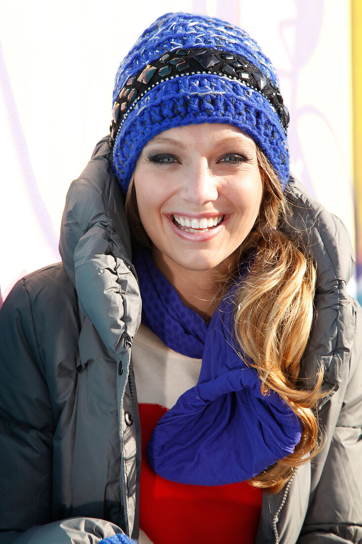 Portrait of happy blonde woman wearing winter jacket and hat, laughing