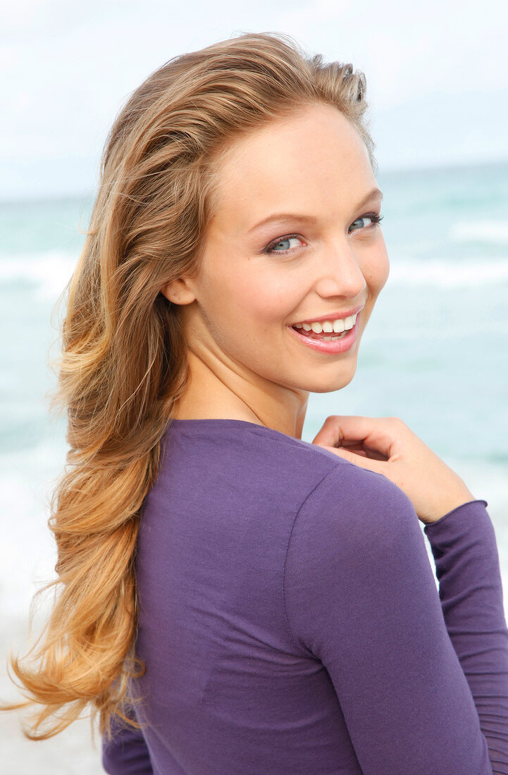 Portrait of beautiful blonde woman wearing purple top, smiling