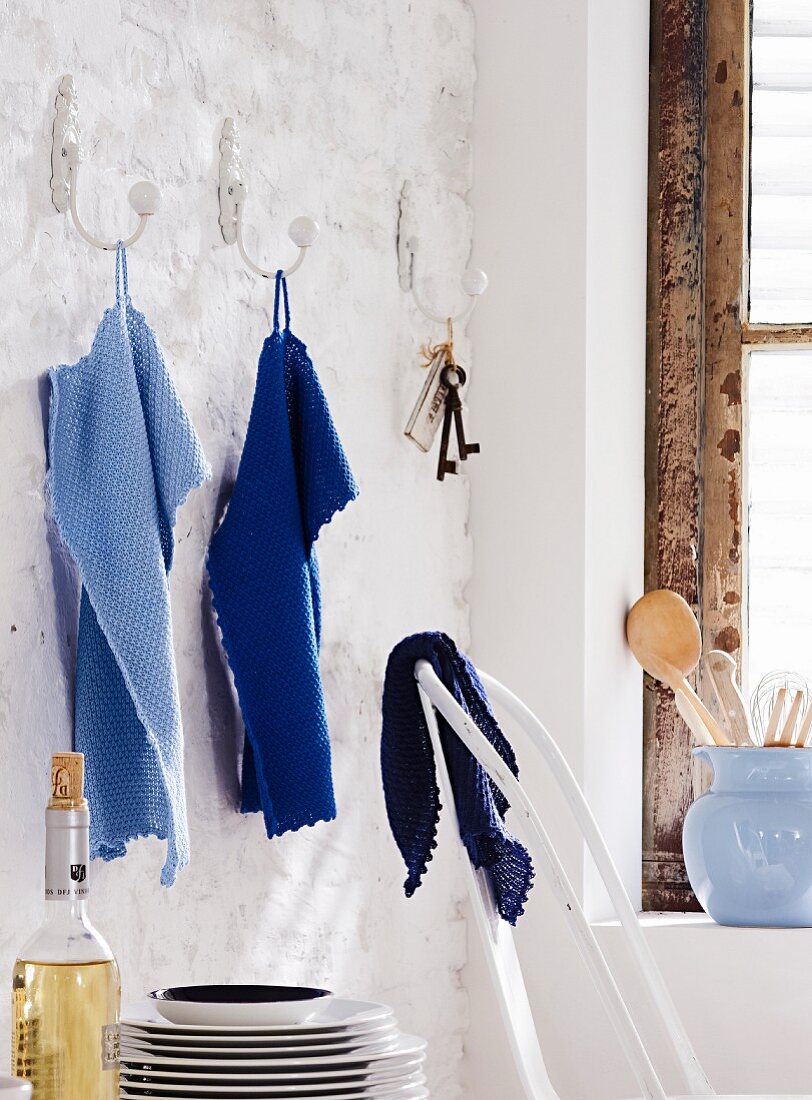 Blue, knitted towels hanging on wall hooks