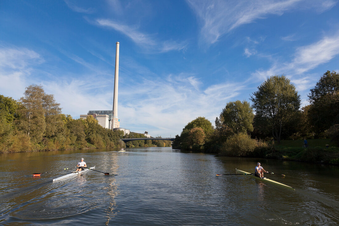 Nina Wengert kayaking in river against power station, Saarland, Germany