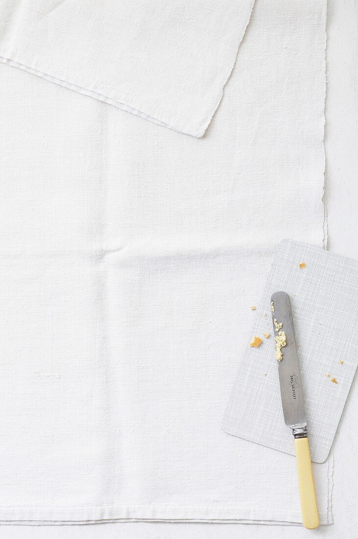 A used board and a knife on a linen cloth (seen from above)