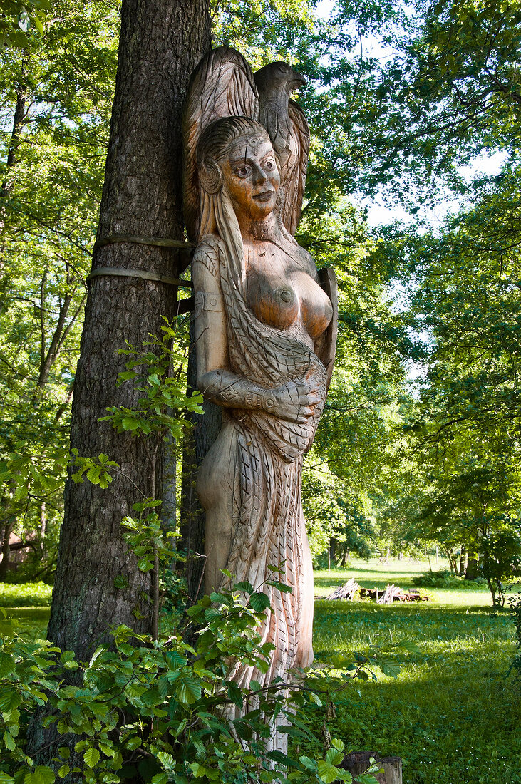 Wooden sculpture besides tree in Galindia Mazurski Eden, Warmia Masuria, Poland