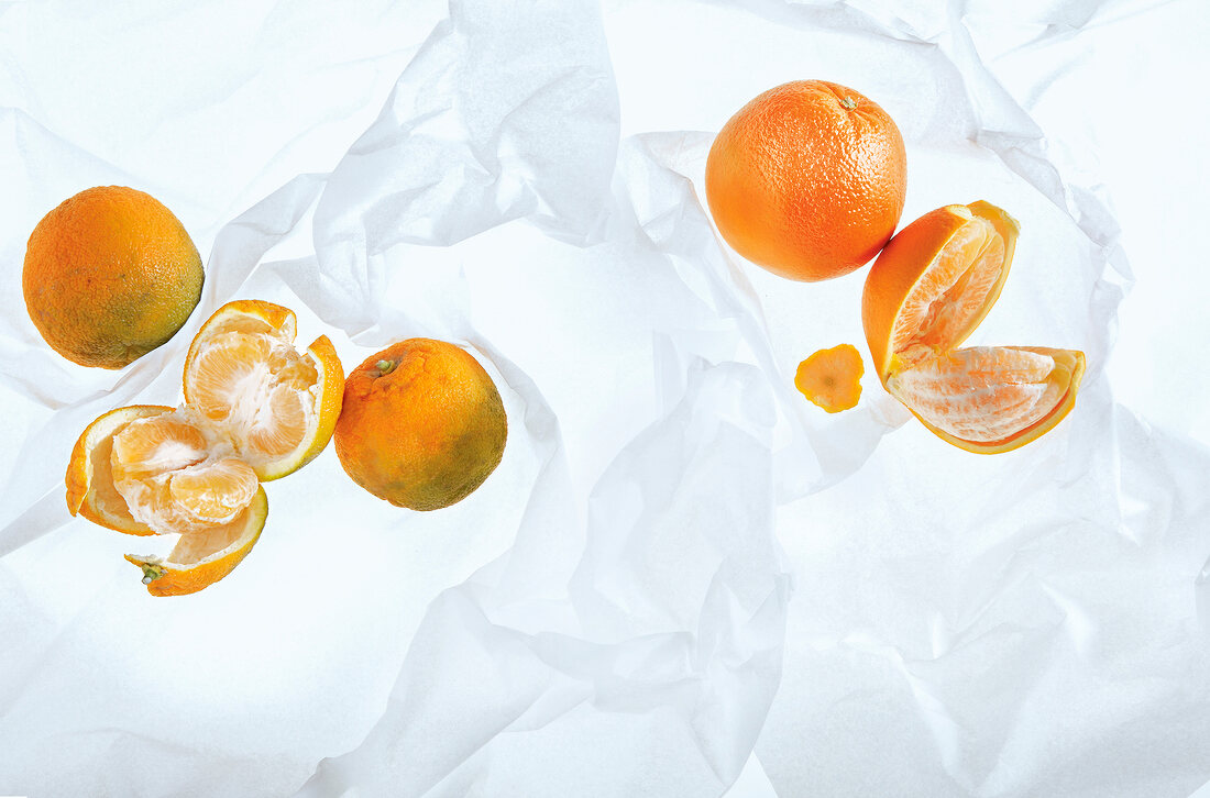Whole and halved oranges with peel on white background