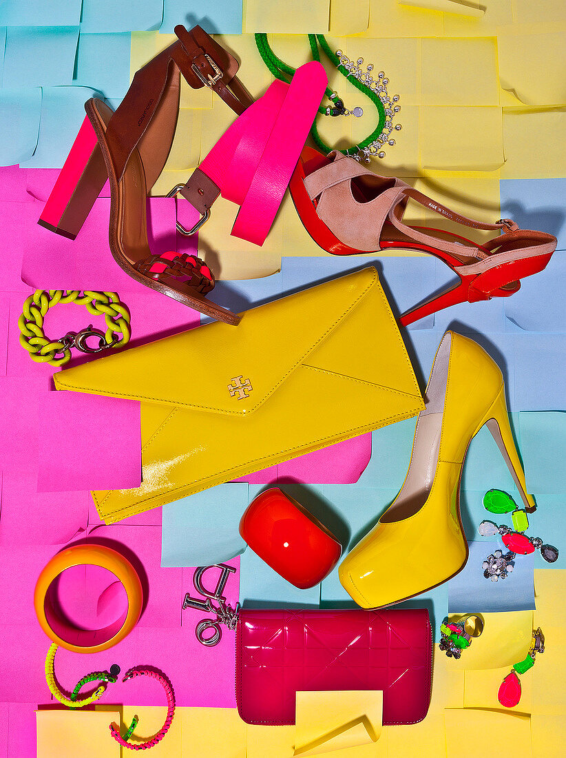 Colourful shoes, handbag and jewellery on multi coloured background