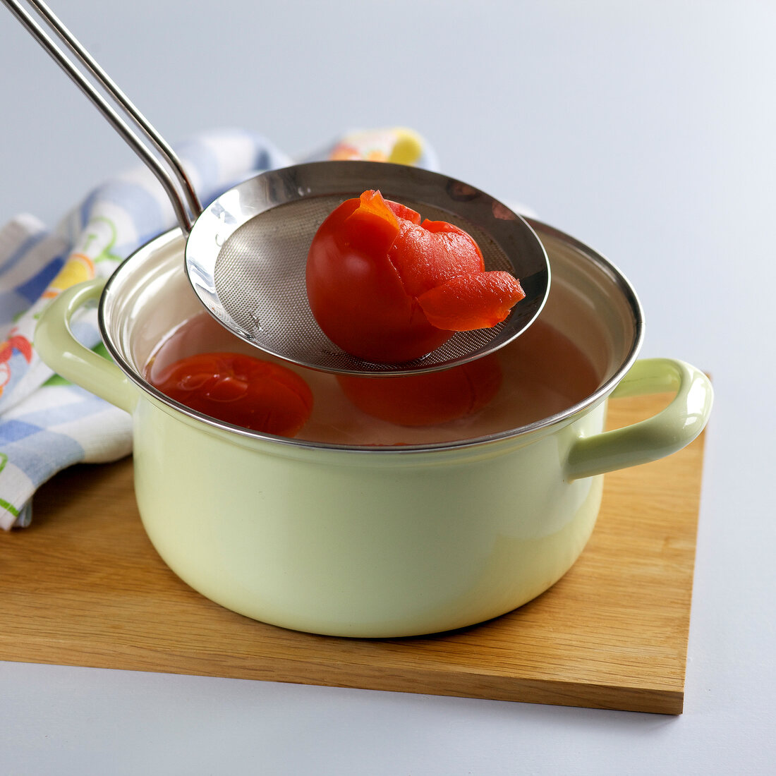 Peeled tomatoes being removed with sieve from casserole, step 2