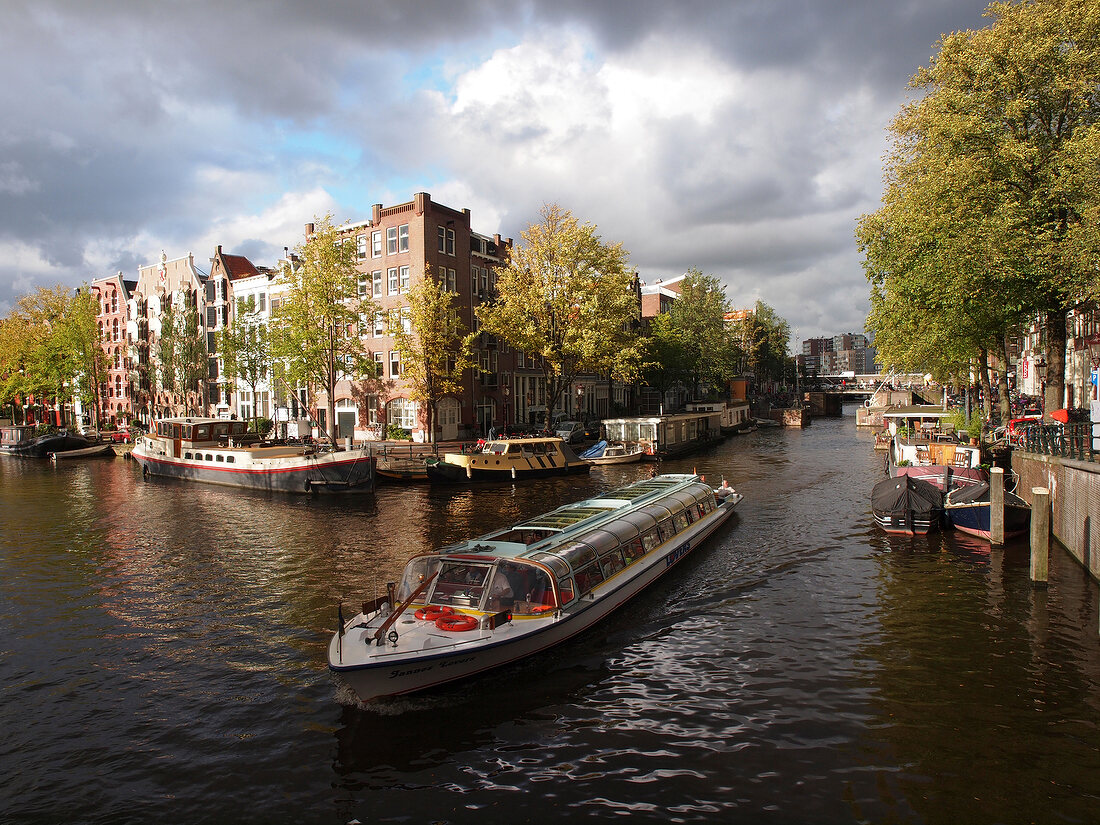 Ferryboats at canal with canal houses in background, Amsterdam, Netherlands