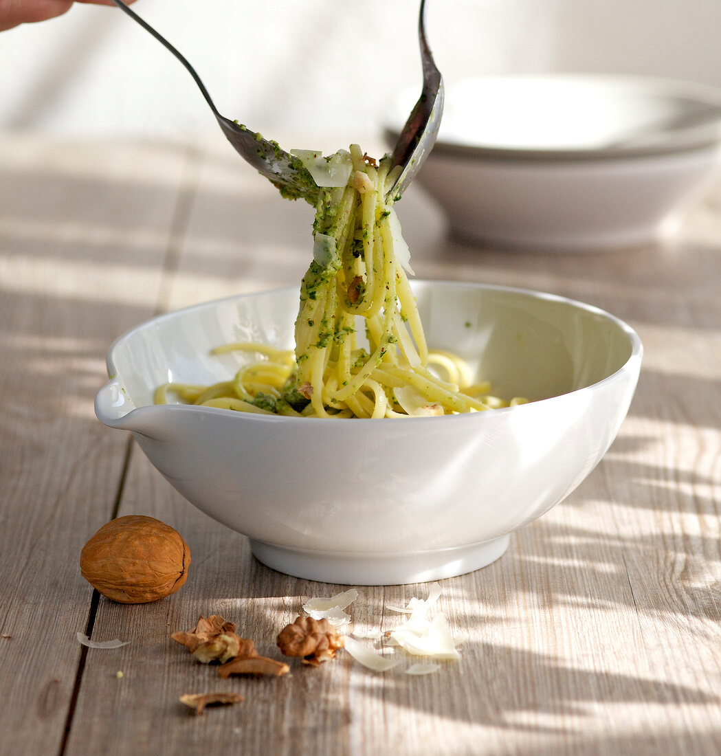 Mixing pasta with walnut pesto in bowl