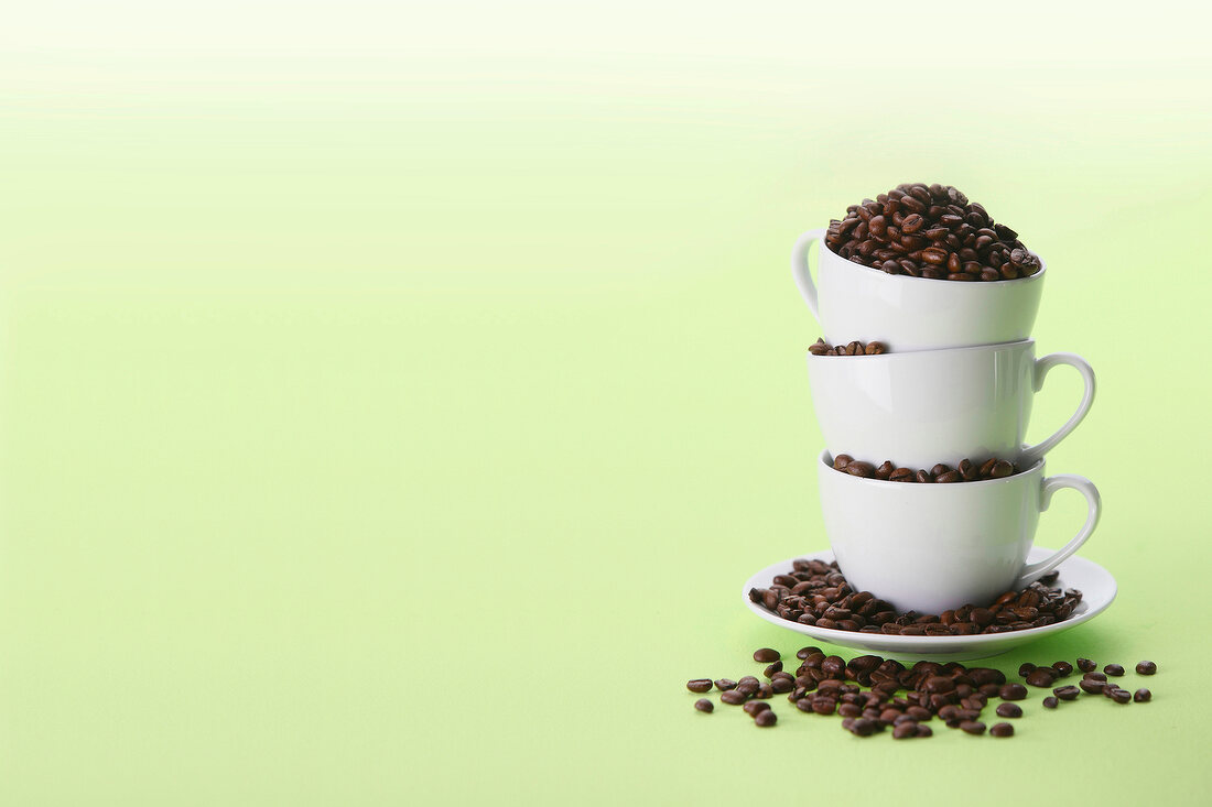 Stack of saucer and coffee cups with coffee beans