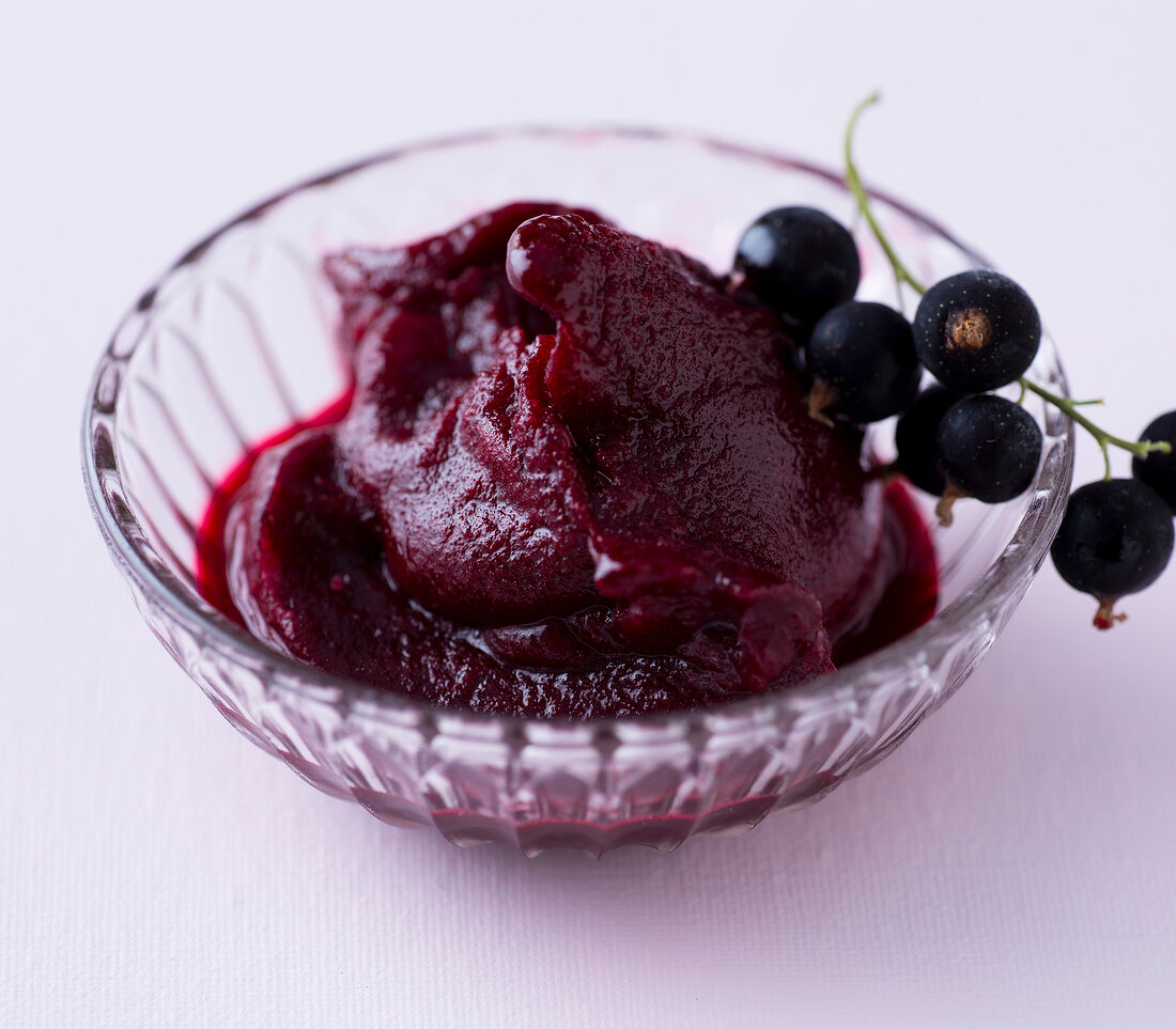 Blackcurrant sorbet with bunch of berries in glass bowl 
