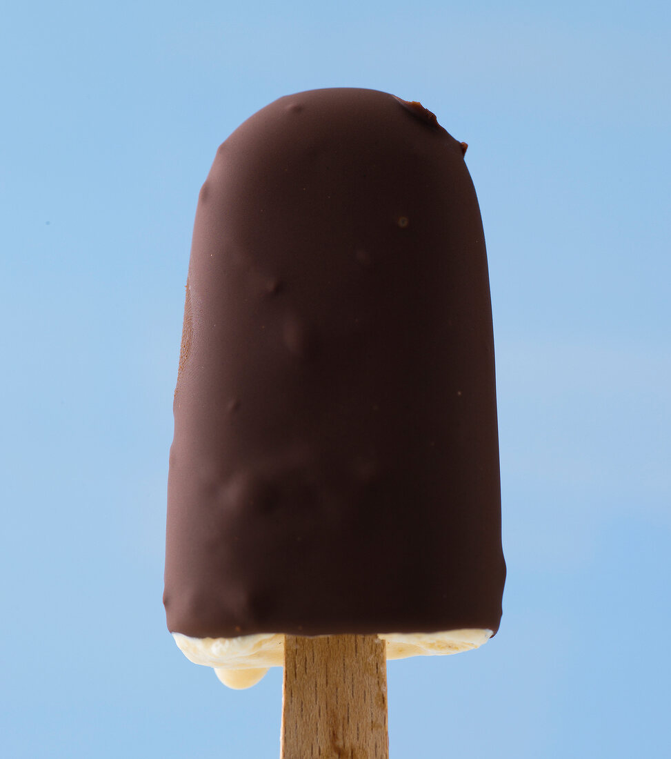 Close-up of ice lolly with chocolate coating against blue background