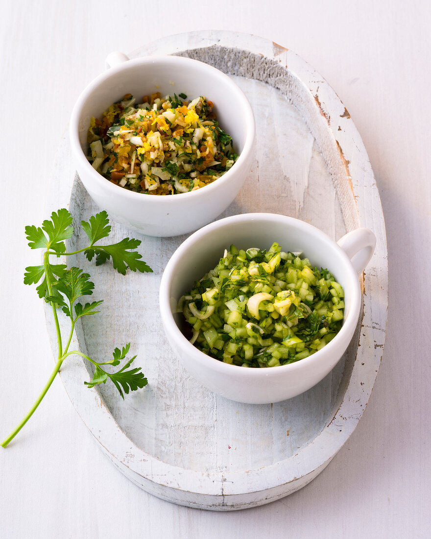 Two cups of lemon fennel salsa and coriander salsa on tray