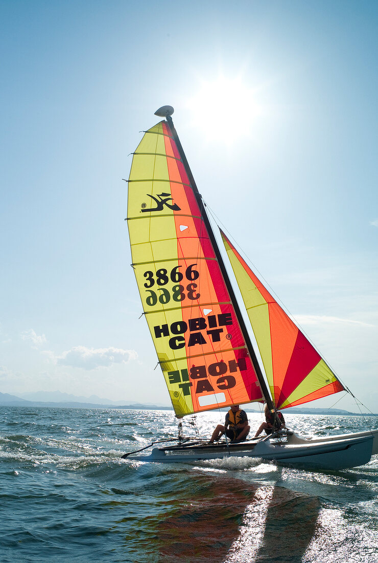 People seated on sailboat in sea, Chiemsee, Bavaria, Germany