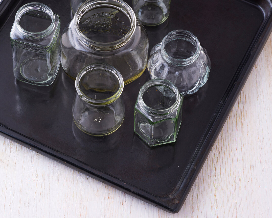 Various types of sterilized glass jars on baking tray for preserving pesto chutney, step 1