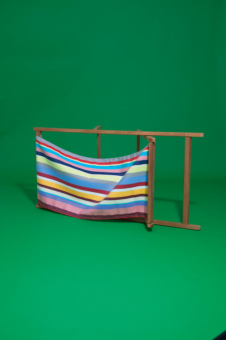 Folding deck chair with stripes pattern on green background
