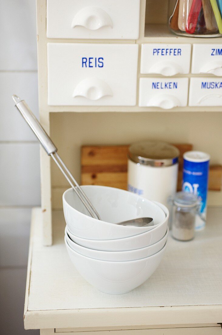 Gestapelte weiße Schälchen auf Küchenschrank in Studentenküche