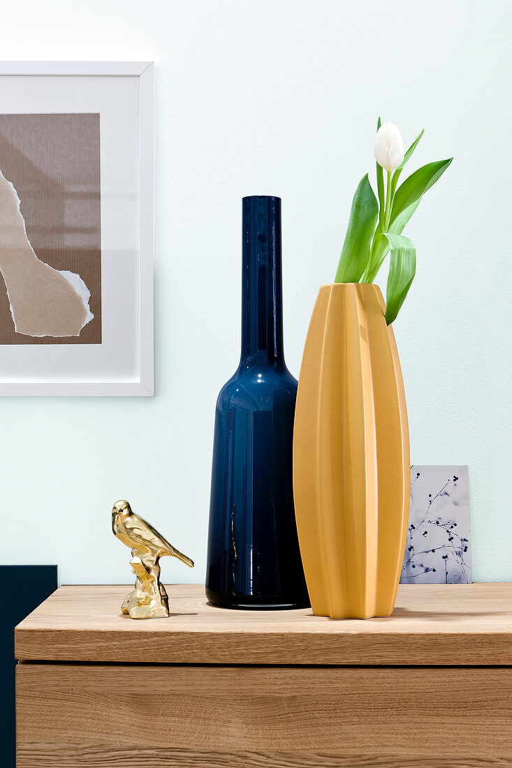 Colourful vases and golden bird paperweight on table