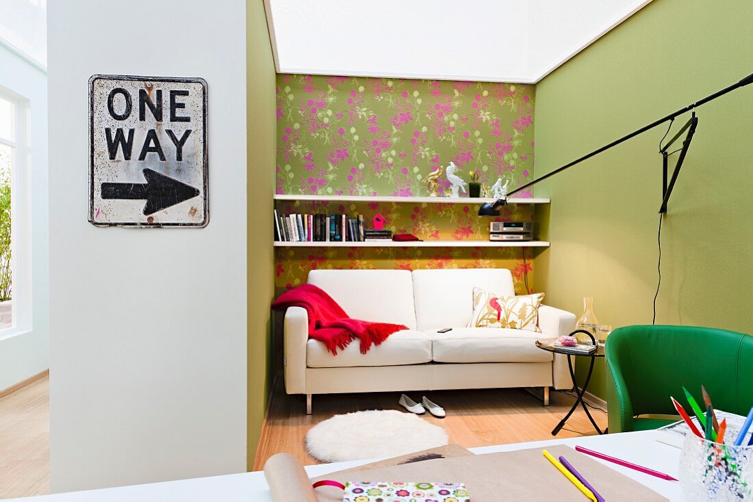 Niche in living room with patterned wallpaper, sofa & wall-mounted shelving