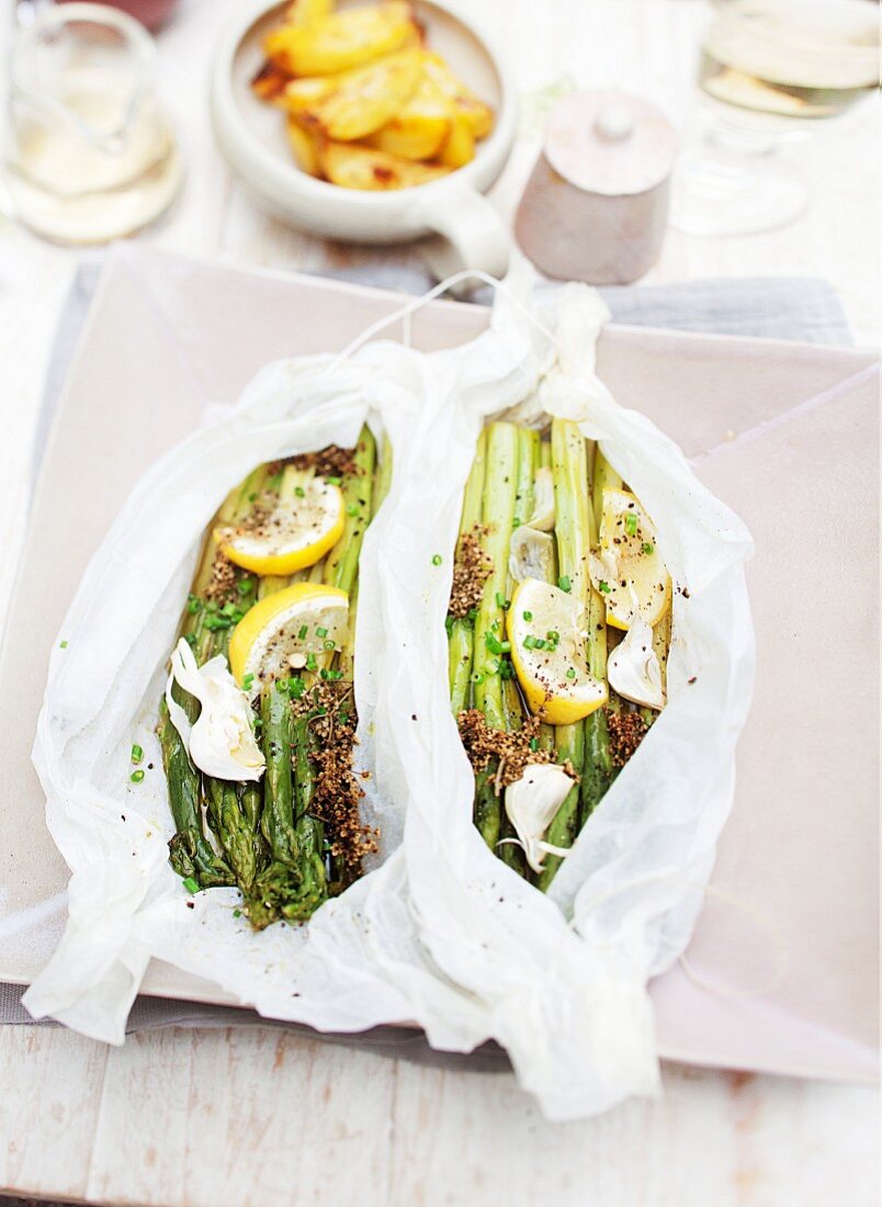 Gratinated green asparagus with lemons and garlic in parchment paper