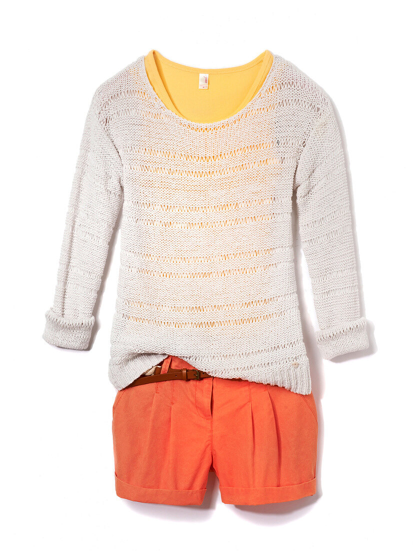 Close-up of white chunky knit sweater and orange shorts on white background