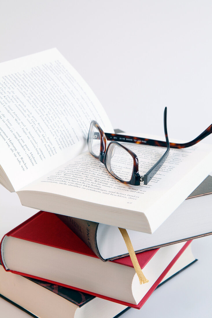 Close-up of stack of books with spectacles on it