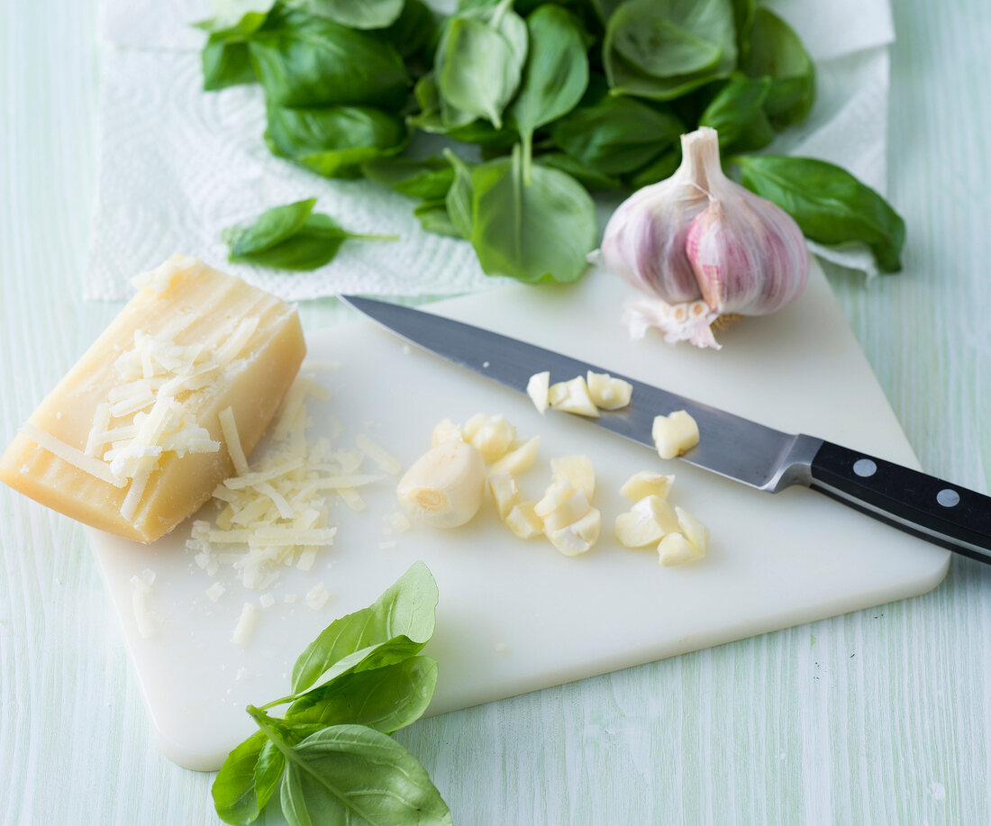 Garlic being chopped on cutting board for preparation on vegetarian Italian pesto, step 1