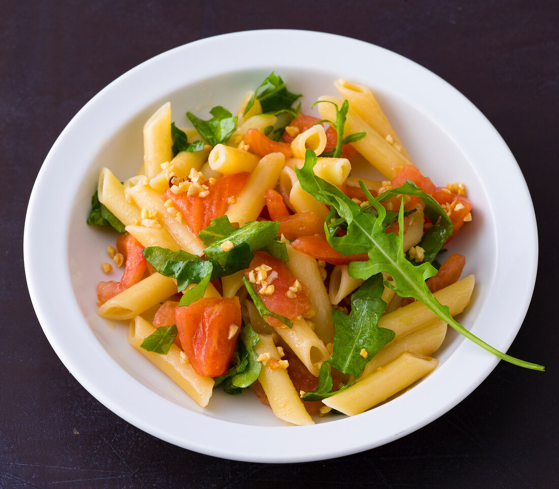 Penne with tomatoes and arugula on plate