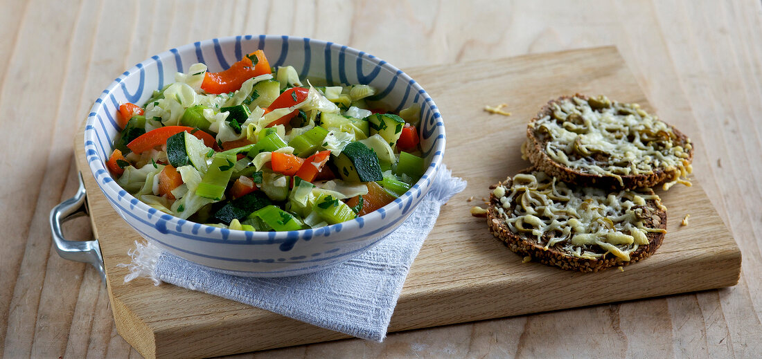 Vegetable stew in bowl with cheese toast on wooden board