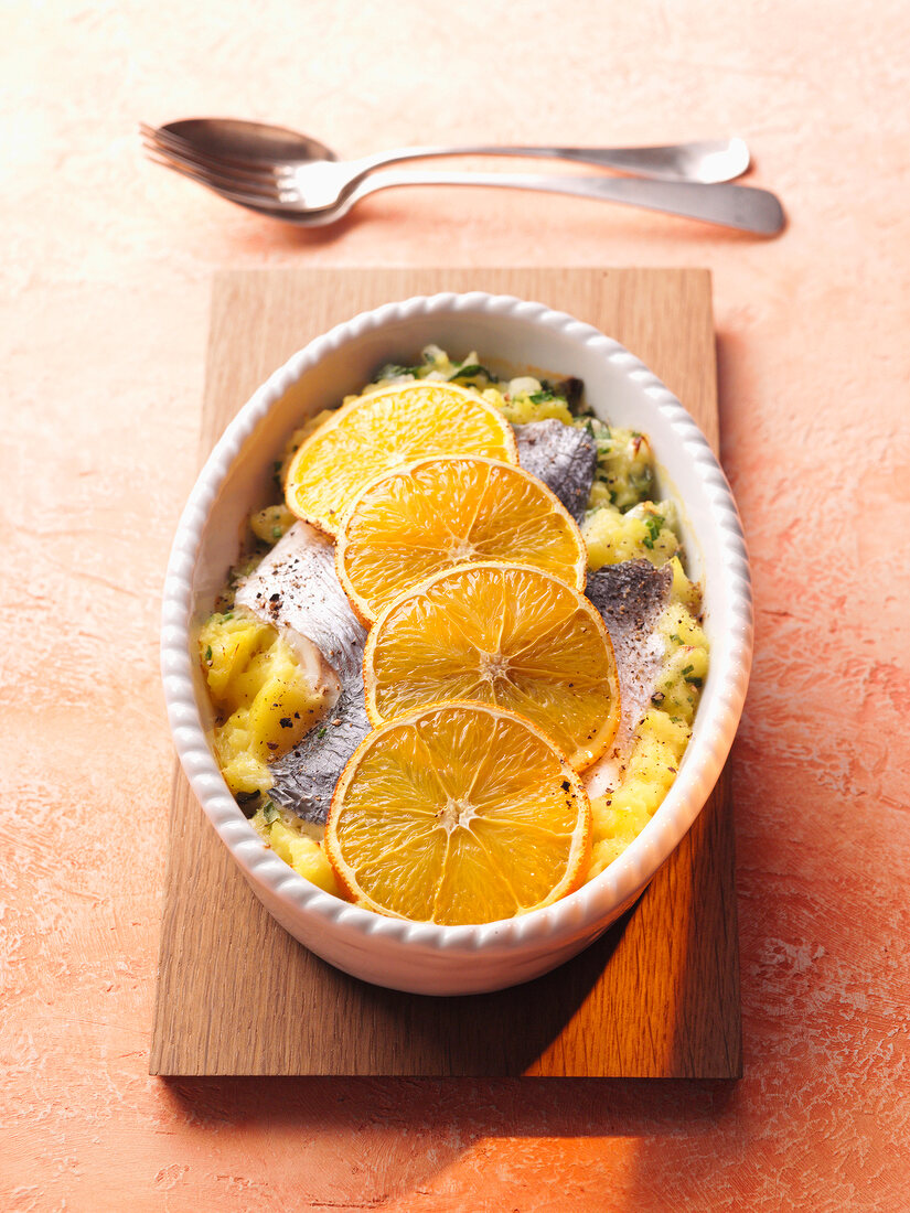 Orange slices on mullet in mashed potatoes in serving bowl