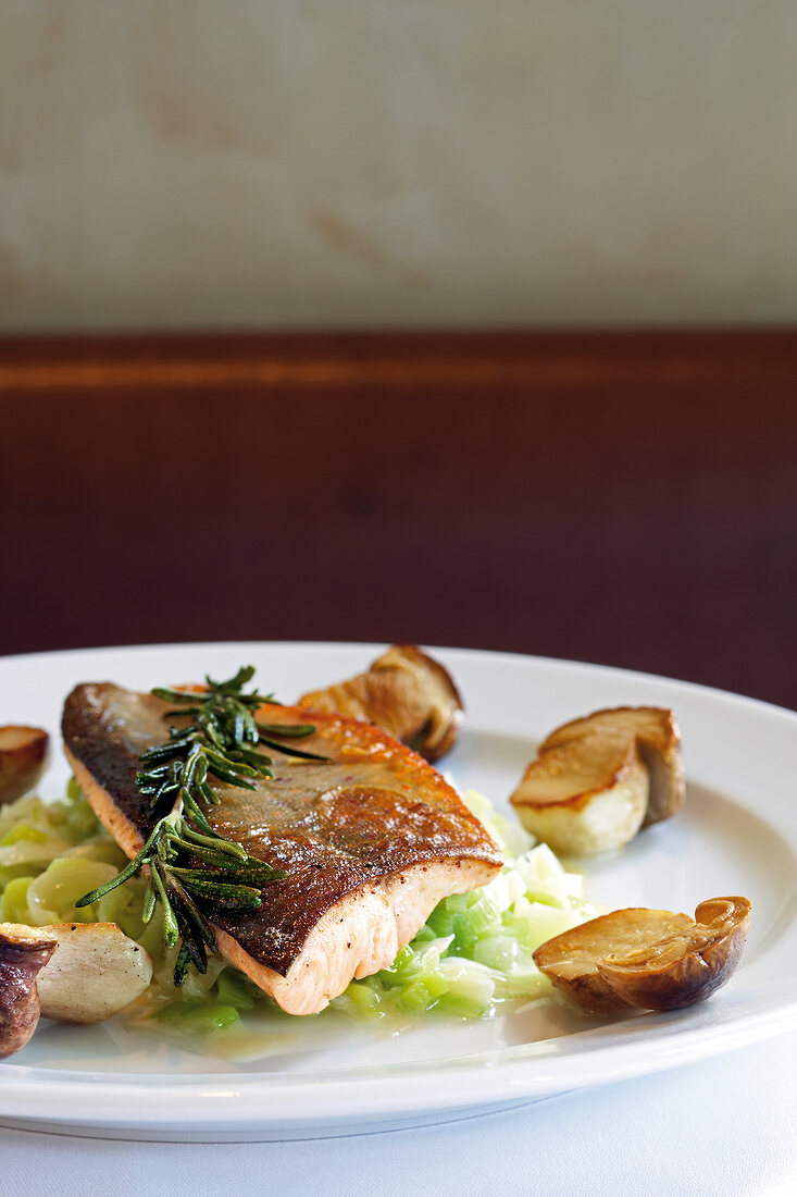 Roasted arctic char fillet with leeks and mushrooms on plate