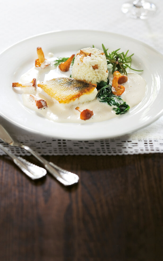 Fried zander fillet with chanterelle risotto and spinach on plate