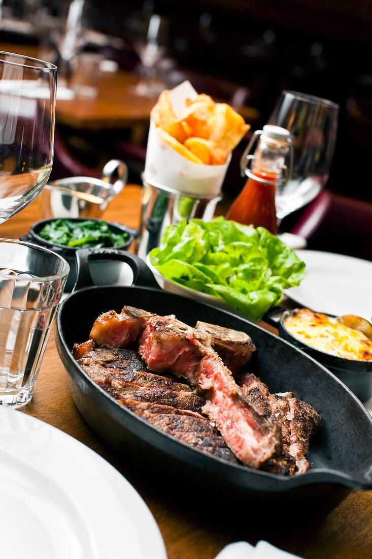 Steaks made of longhorn beef in pan on table laden with food