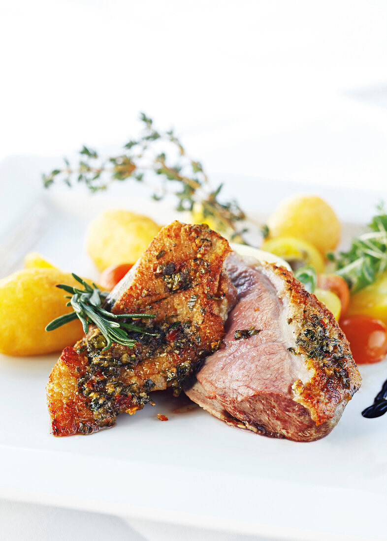 Close-up of duck breast with potatoes and rosemary on plate