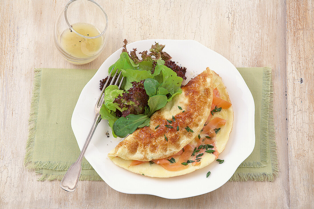 Salmon omelette with leaves salad on plate