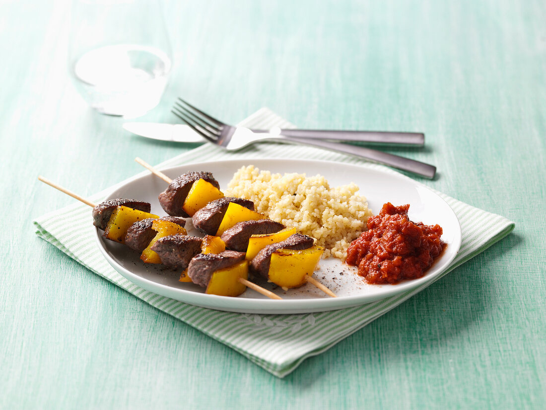 Paprika lamb skewers with bulgur of sunflower seeds on plate