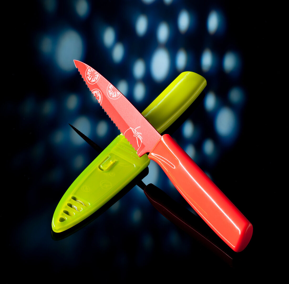 Knife with knife cover of red and green coating on black background