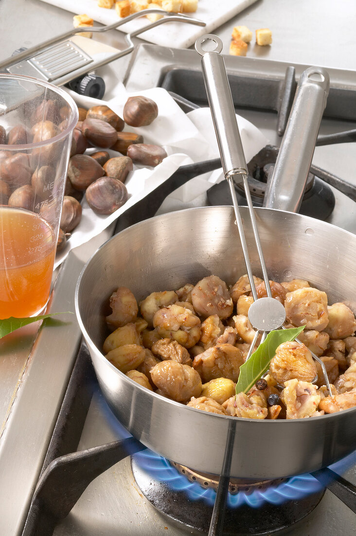 Chestnuts and shallots being cooked with butter and spices in sauce pan