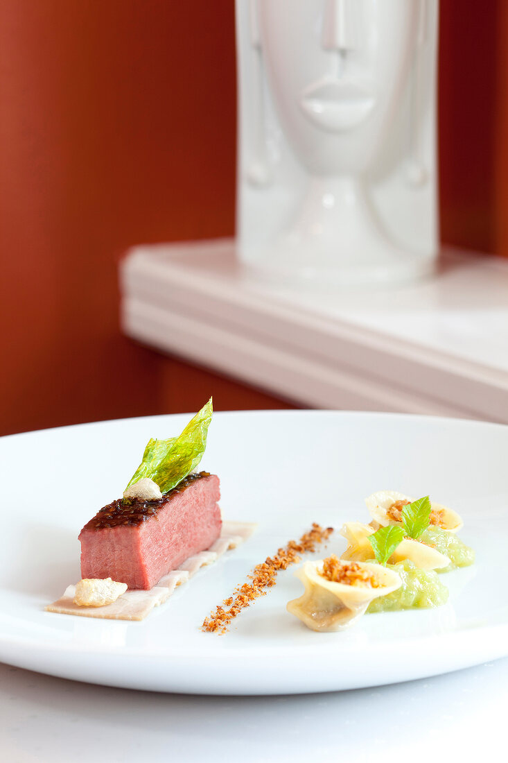 Close-up of marinated breast of Iberian pig with tortellini on plate