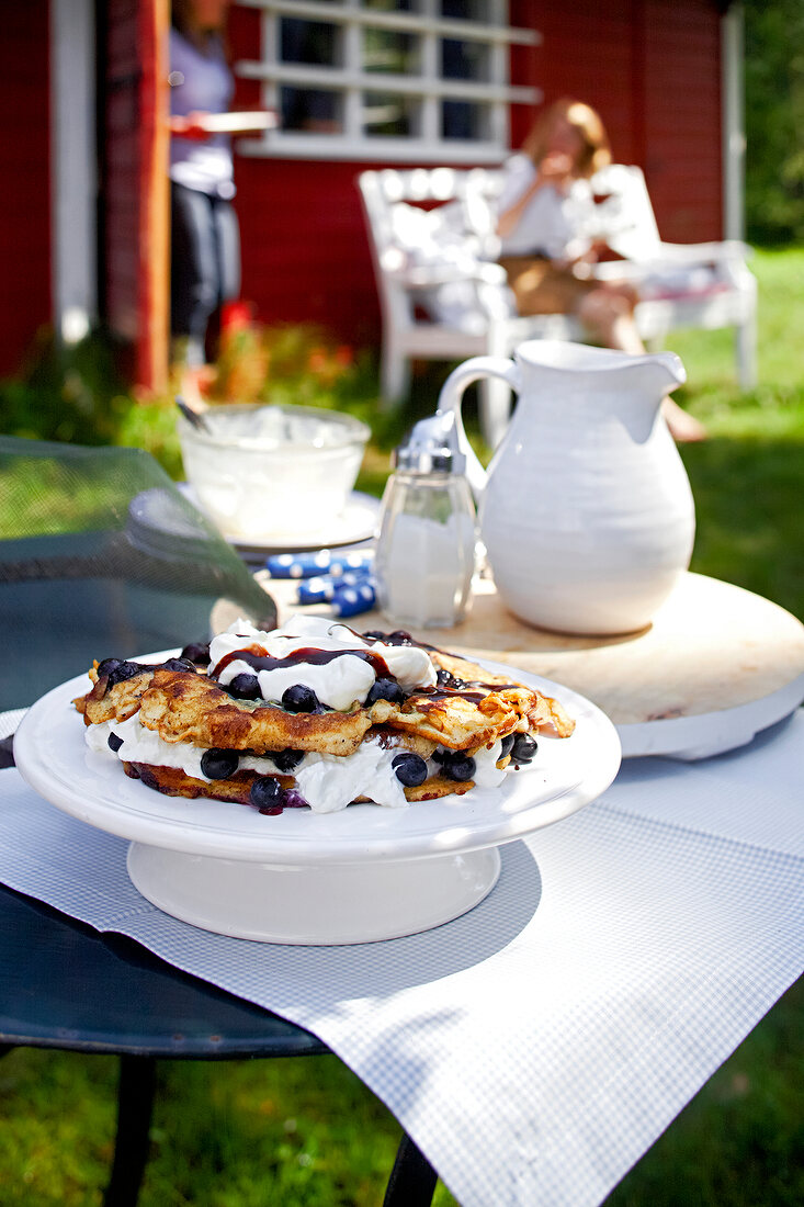 Blueberry pancakes with whipped cream and chocolate sauce in serving dish