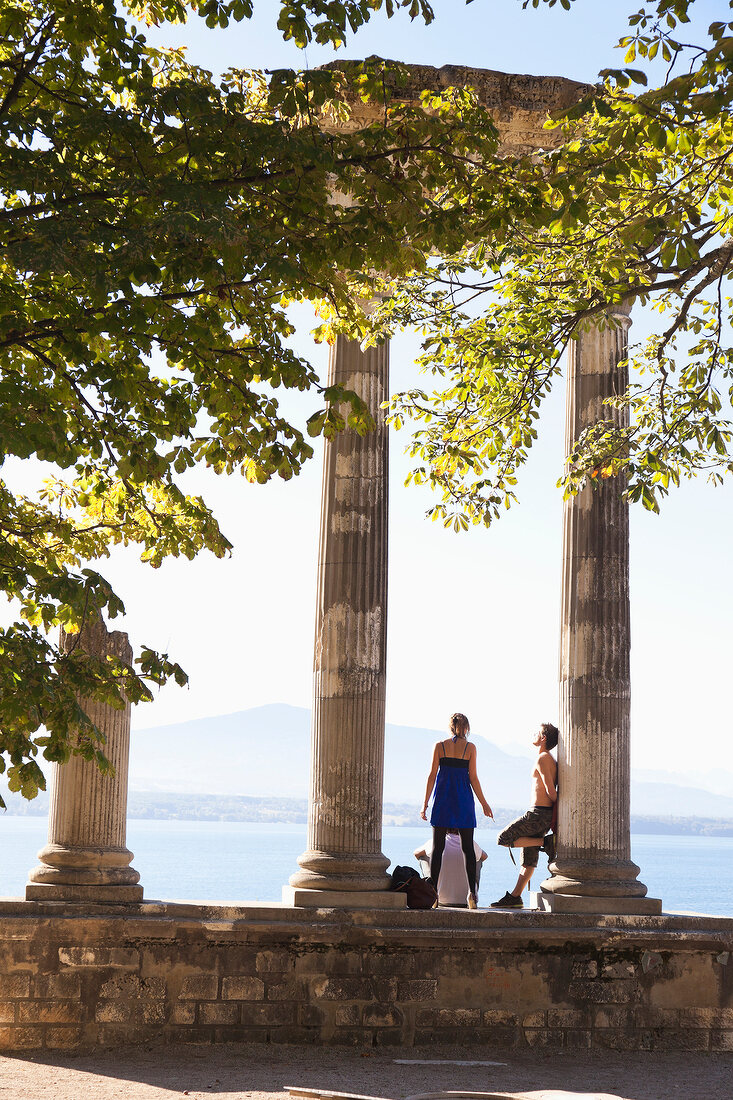 People standing between columns near lake Geneva, Riviera-Pays-d'Enhaut, Switzerland