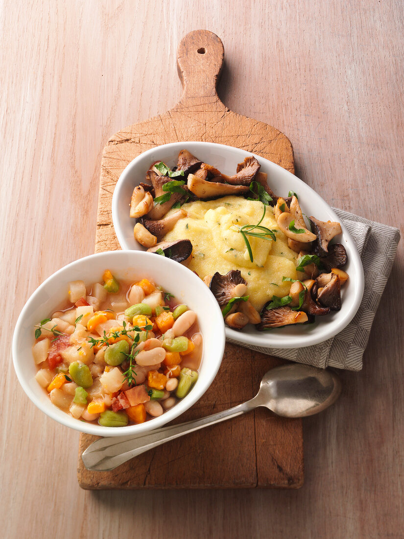 Beans stew and stirred polenta on wooden serving board